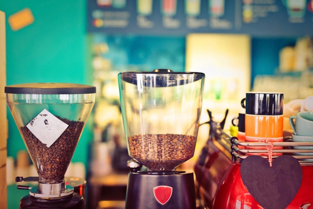 Two café grinders with hoppers full of roasted coffee beans