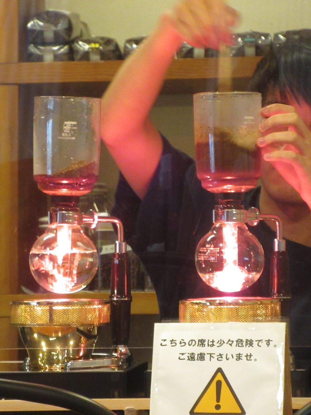 Siphon coffee brewers on a counter with water risen into the upper chambers